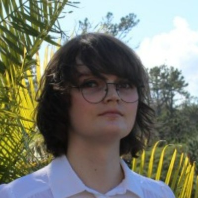 A headshot of Hazel Full, standing in front of some New Zealand ferns.